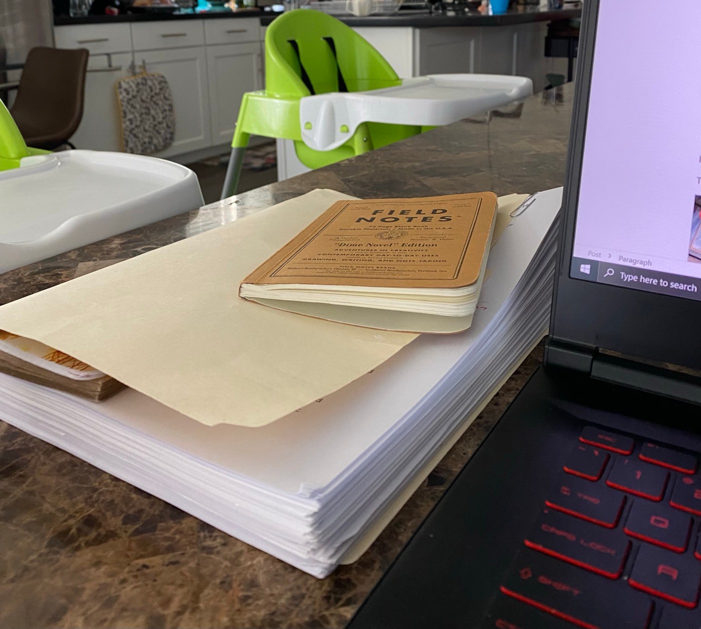 a stack of notebooks next to a laptop