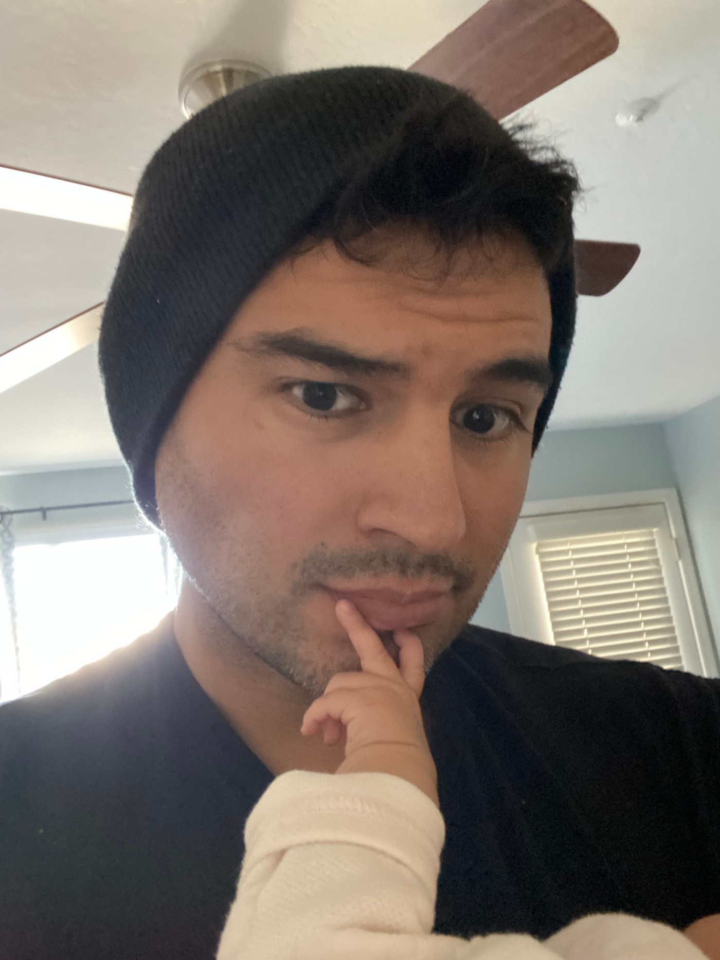 A father, holding his baby daughter, trying to go to sleep, as she grabs his face.